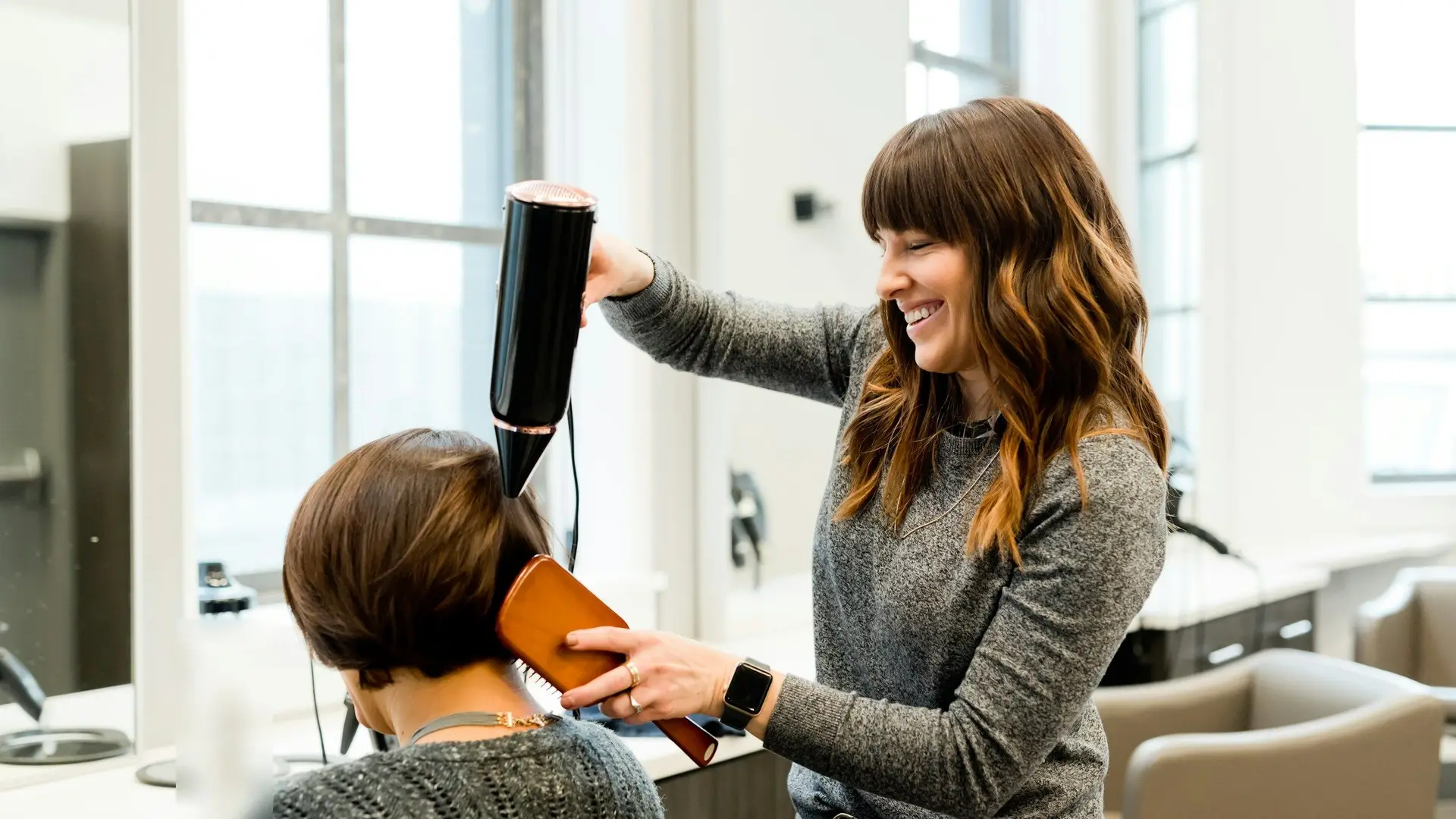 Coiffeuse föhnt einer Kundin die Haare